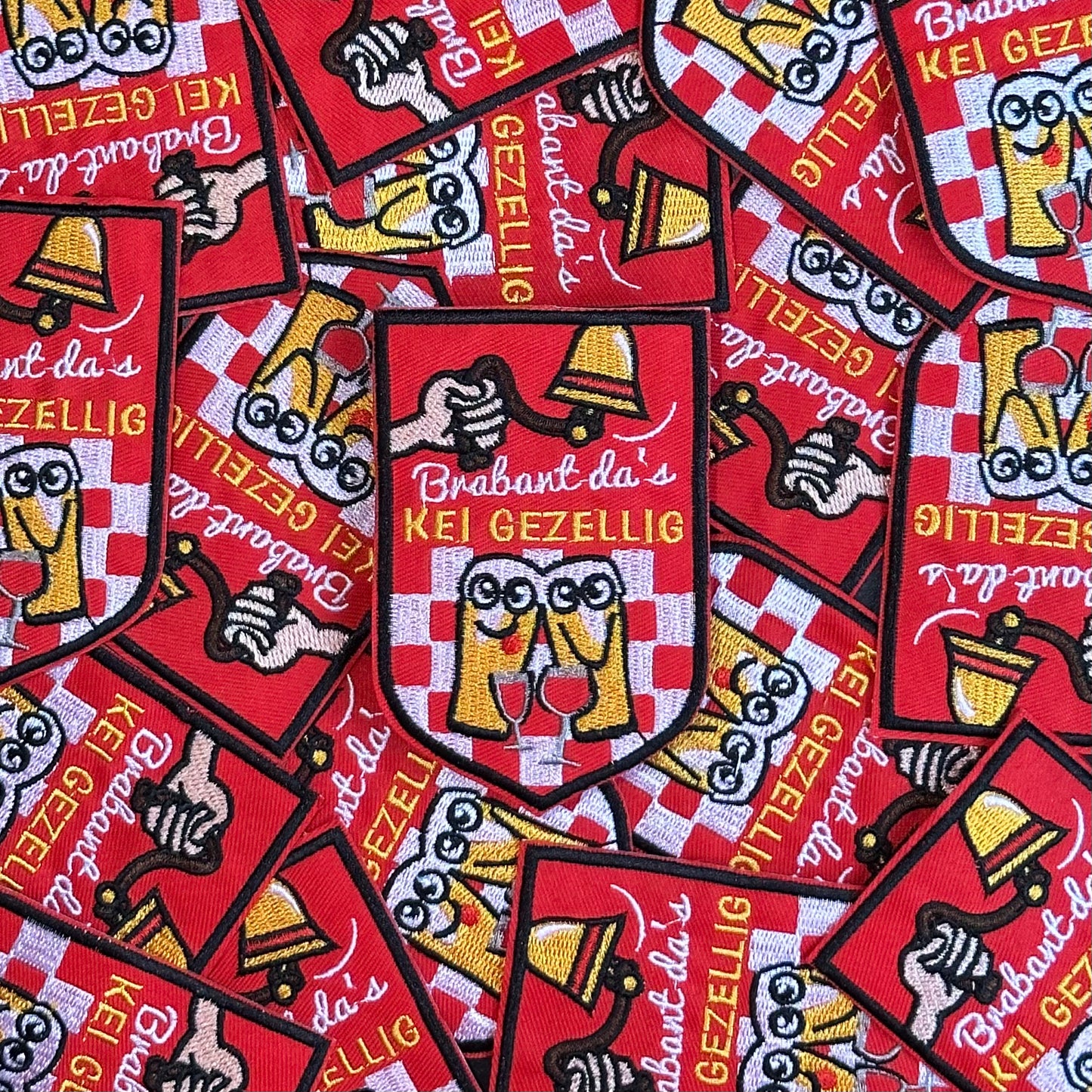 Een rood embleem, waarbij er aan een bel getrokken word, twee biertjes gezellig met een wijntje zitten en de tekst 'Brabant da's KEI GEZELLIG' is opgenomen.