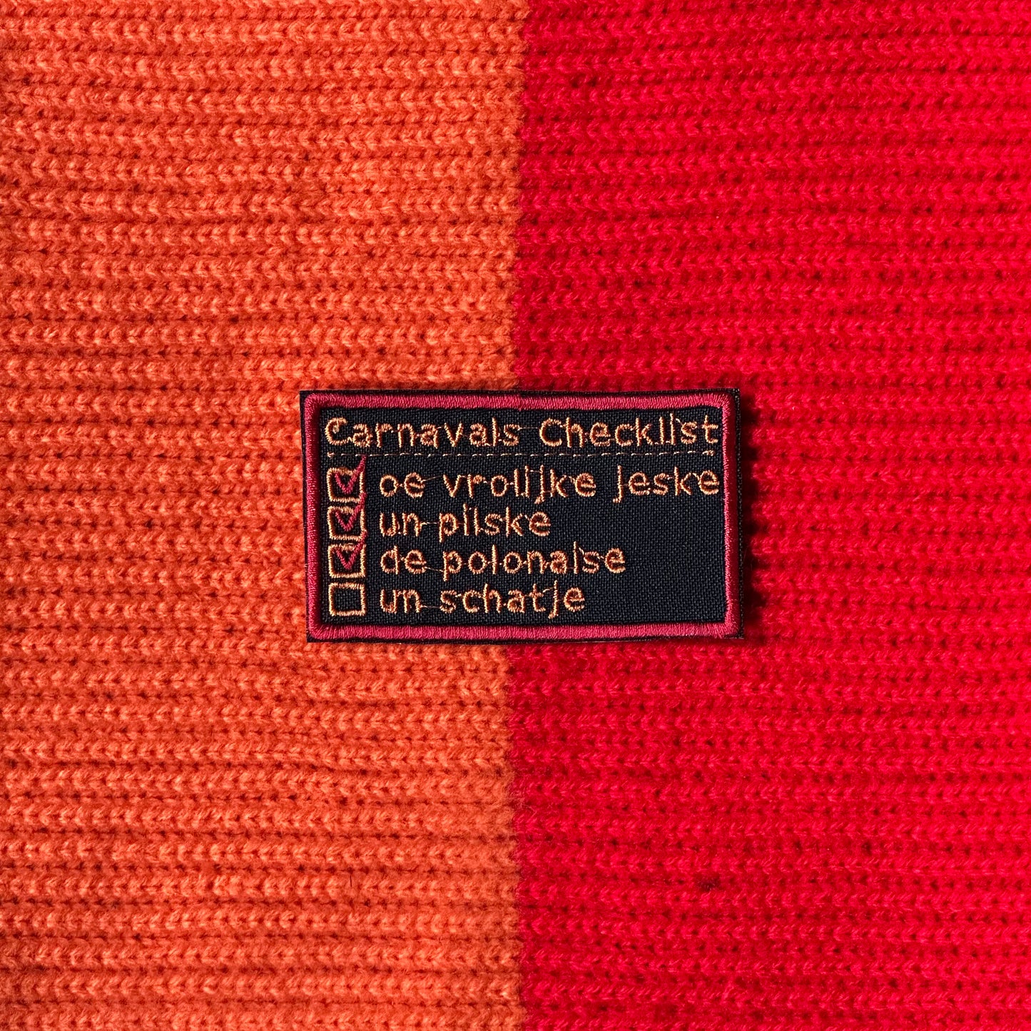 Een rechthoeking vlak, met een zwarte achtergrond. Hierop is met oranje letters een carnavalschecklist opgenomen, die wordt afgevinkt met rode vinkjes.