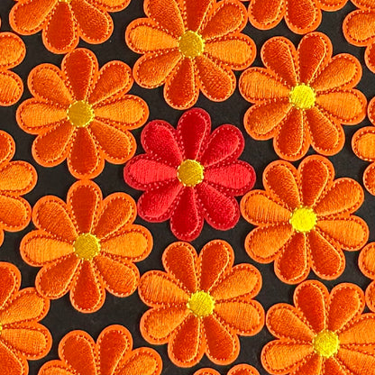 Een klein Bloemvormig Kielegat embleem in de kleuren rood of oranje.
