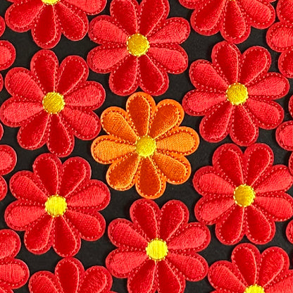 Een klein Bloemvormig Kielegat embleem in de kleuren rood of oranje.