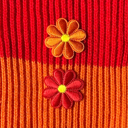 Een klein Bloemvormig Kielegat embleem in de kleuren rood of oranje.