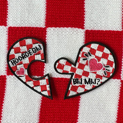 Een in gebroken hart, wat door een puzzel stukje te verbinden is aan elkaar. De achtergrond van dit hartje is een brabantse vlag, en op het linkerhart deel staat de tekst 'Hooroe gij' en op het rechterhart deel staat de tekst 'bij mij?'