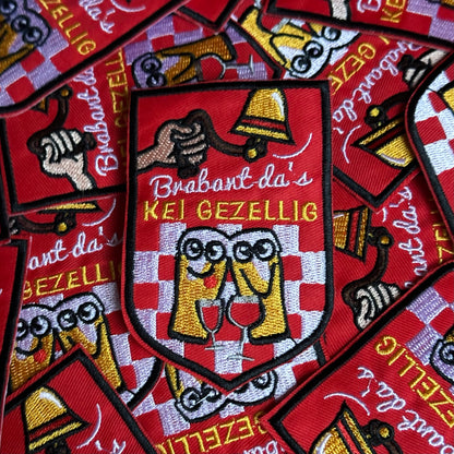 Een rood embleem, waarbij er aan een bel getrokken word, twee biertjes gezellig met een wijntje zitten en de tekst 'Brabant da's KEI GEZELLIG' is opgenomen.