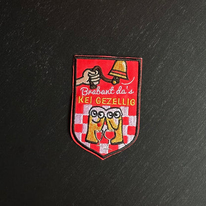 Een rood embleem, waarbij er aan een bel getrokken word, twee biertjes gezellig met een wijntje zitten en de tekst 'Brabant da's KEI GEZELLIG' is opgenomen.