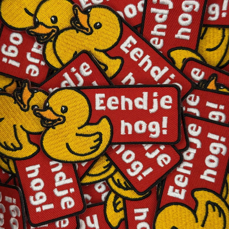 Stapel carnavalsemblemen met badeendje voorzien van text 'Eendje nog!'. Badeendje is geel met een oranje snavel en de tekstbox is rood, perfect kielegat embleem.