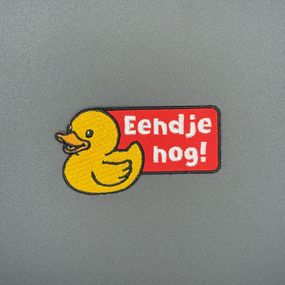 Embleem van badeendje met tekst 'Eendje nog!'. Badeendje is geel met een oranje snavel en de tekstbox is rood, perfect kielegat embleem.