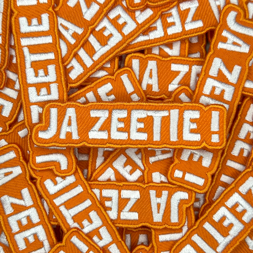 Embleem met text: "Ja Zeetie!", groepsfoto