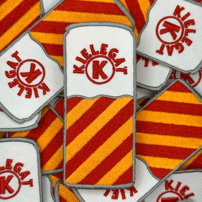 Een blikjes embleem met rood-oranje strepen in de kleuren van het Kielegat, met de tekst ‘Kielegat’ om een K heen gebogen. Groepsfoto