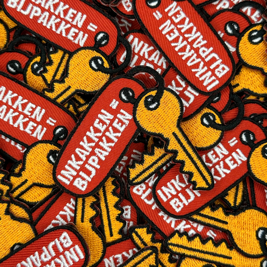 Embleem sleutel met sleutelhanger met text: "inkakken = bijpakken", groepsfoto