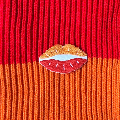 Een Kielegat embleem in de vorm van een kusje in het rood en oranje.