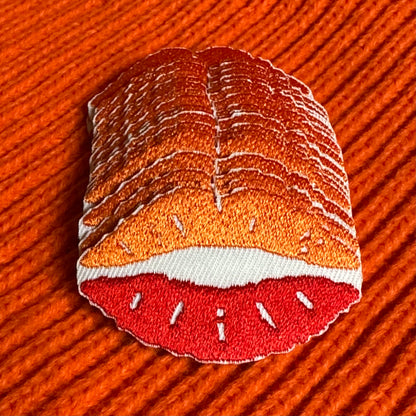 Een Kielegat embleem in de vorm van een kusje in het rood en oranje.