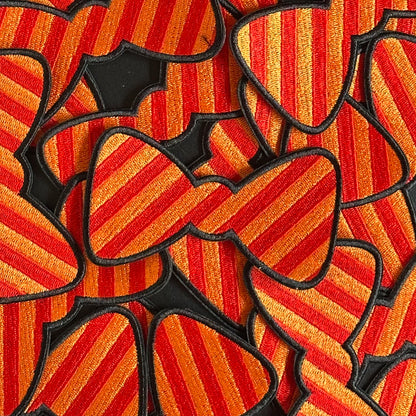 Een Kielegat embleem in de vorm van een strikje die rood en oranje gestreept is.